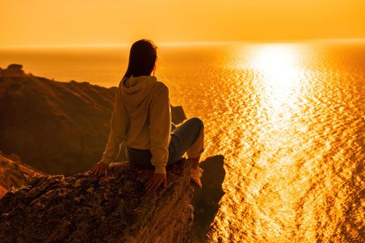 woman traveler drinks coffee with a view of the mountain landscape. A young tourist woman drinks a hot drink from a cup and enjoys the scenery in the mountains. Trekking concept