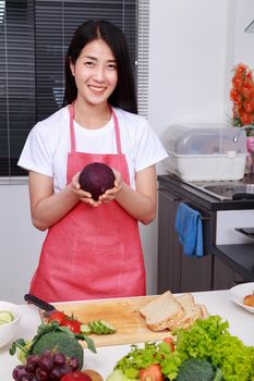 happy woman holding purple cabbage in kitchen room at home