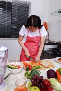 woman cutting carrot in kitchen room at home