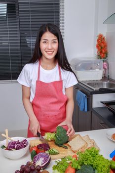 woman using knife to cutting broccoli in kitchen room at home