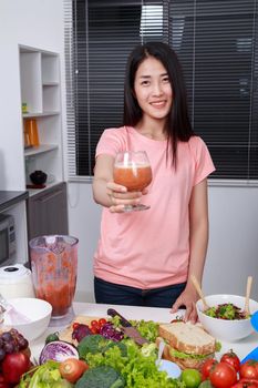 young woman with smoothies in glass at kitchen room