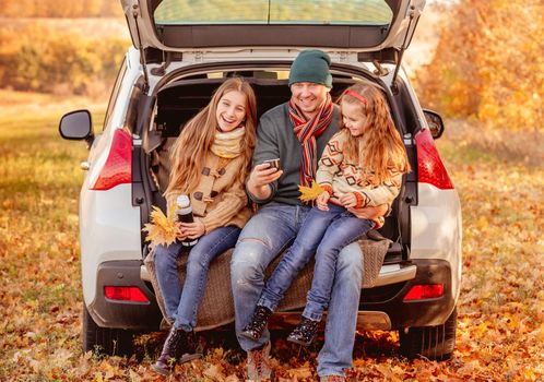 Smiling father with daughters in autumn surroundings