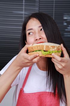 woman eating a sandwich in kitchen room at home