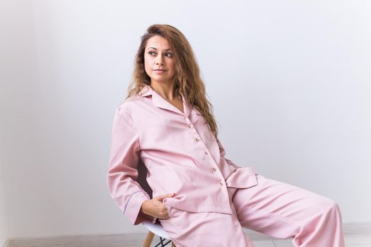 Young attractive woman dressed in beautiful colorful pajama posing as a model in her living room. Comfortable sleepwear, home relaxation and female fashion concept