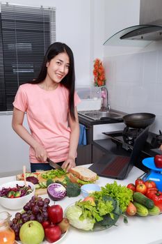 young woman cooking and looking with laptop in kitchen room