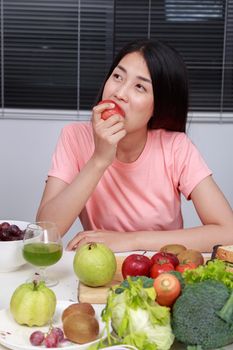 young woman eating red apple in kitchen