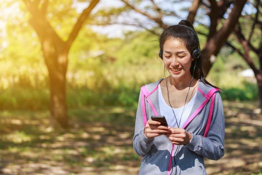 young sporty woman using smartphone with headphone in the park