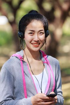 young sporty woman using smartphone with headphone in the park