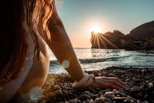 Young woman in swimsuit with long hair practicing stretching outdoors on yoga mat by the sea on a sunny day. Women's yoga fitness pilates routine. Healthy lifestyle, harmony and meditation concept.