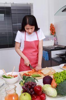 woman cutting carrot in kitchen room at home