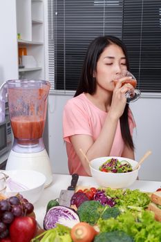 young woman with smoothies in glass at kitchen room