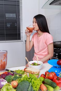 young woman with smoothies in glass at kitchen room