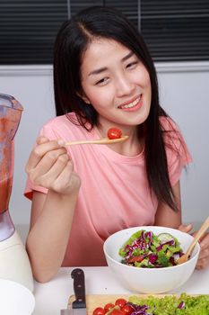 young woman eating salad in kitchen room