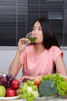 young woman drinking vegetable juice in kitchen