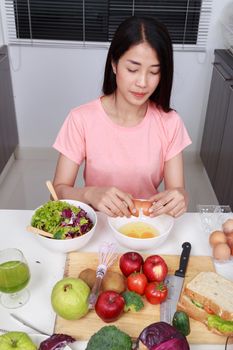 young woman smashing eggs in bowl at kitchen room