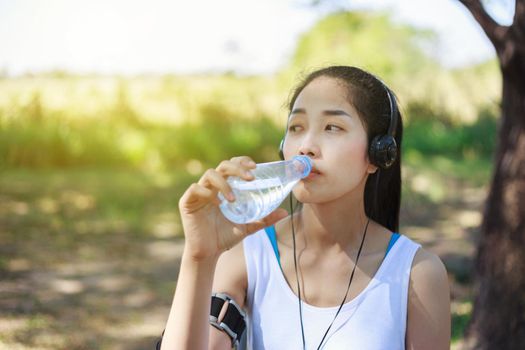 young sporty woman drinking water in the park