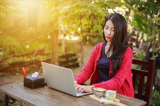 young woman using laptop and drinking coffee in the garden