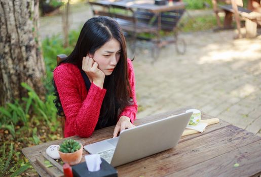 young woman using laptop and drinking coffee in the garden