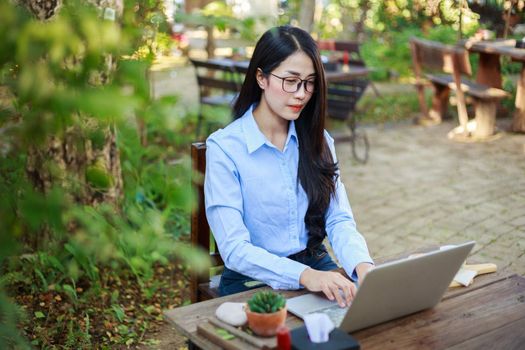 young woman using laptop and drinking coffee in the garden