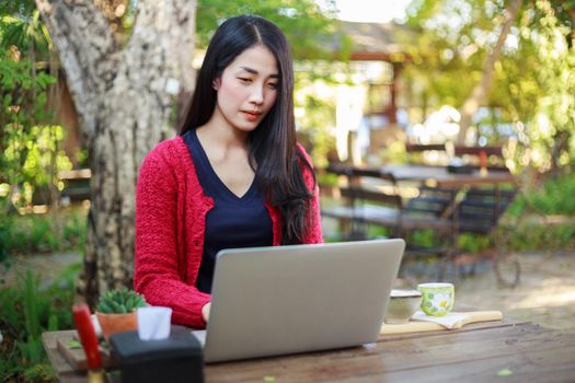 young woman using laptop and drinking coffee in the garden