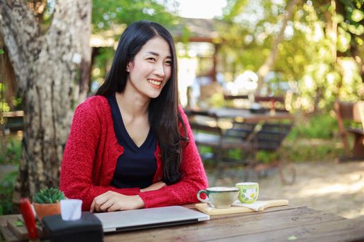 portrait of young woman with laptop and coffee in the garden