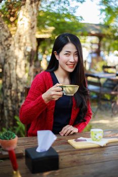 young woman sitting on a table and drinking a cup of coffe in the garden