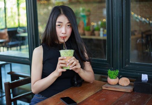 young woman dinking ice green tea latte in the cafe