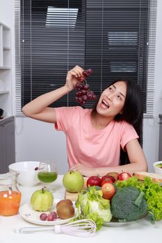 young woman eating grape in kitchen room