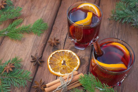 Christmas mulled wine on a wooden background with spices and spruce branches and dried orange