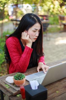 young woman using laptop and drinking coffee in the garden