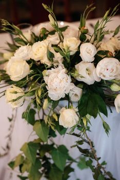 The presidium of the newlyweds in the banquet hall of the restaurant is decorated with candles and green plants, wisteria hangs from the ceiling