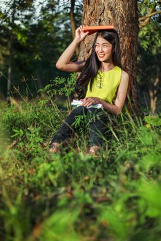 young woman sitting and holding a book in the park