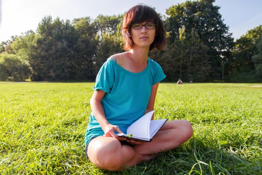 Beautiful girl reading a book on a summer meadow