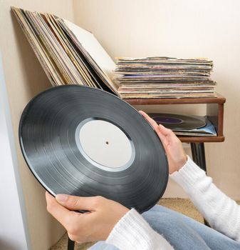 Woman choosing vinyl records at home for listening.