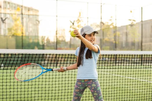 Little girl trying to play tennis on outdoor court