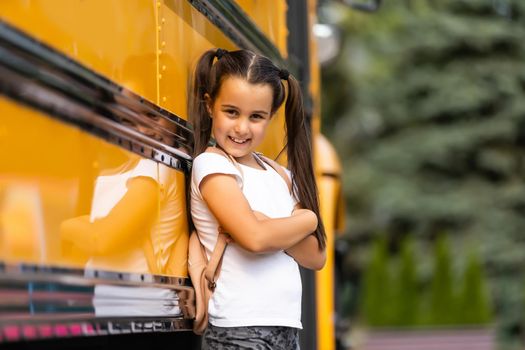 Cute girl with a backpack standing near bus going to school posing to camera pensive close-up