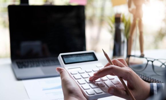 woman working with calculator, business document and laptop computer notebook.