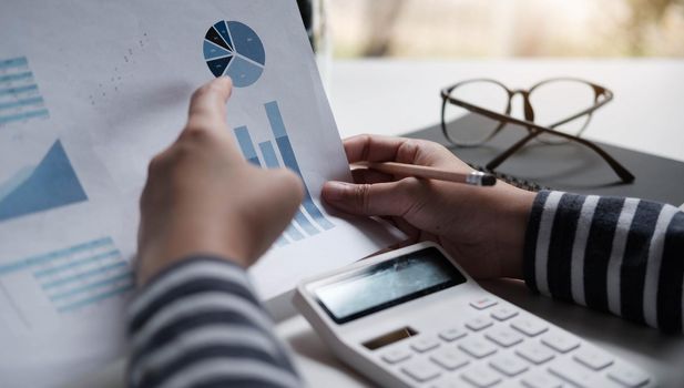 Business women reviewing data in financial charts and graphs.