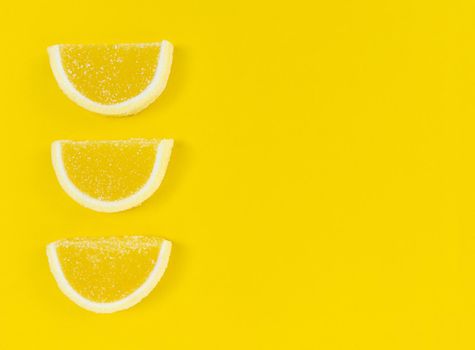 Marmalade lemon slices in sugar on a yellow background with copy space.