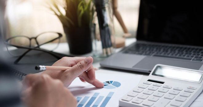 Soft focus business woman using a calculator to calculate the numbers on working desk.