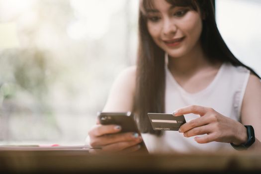 Woman's hand typing on laptop while doing online shopping. Girl using smart phone online purchase