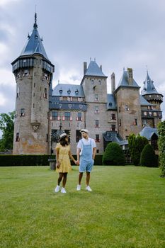 Castle de Haar Utrecht, couple men and woman mid age European and Asian visit De Haar Castle in Dutch Kasteel de Haar is located in Utrecht Netherlands during Spring with flowers in the garden