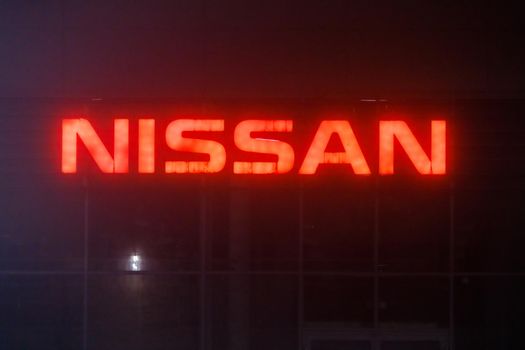 neon red sign Nissan on car dealership center at foggy night - Tula, Russia, 02 11 2021