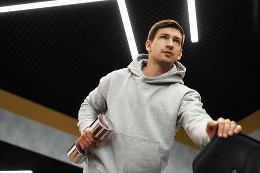 Determined handsome young male working out in gym with dumbbells, close up