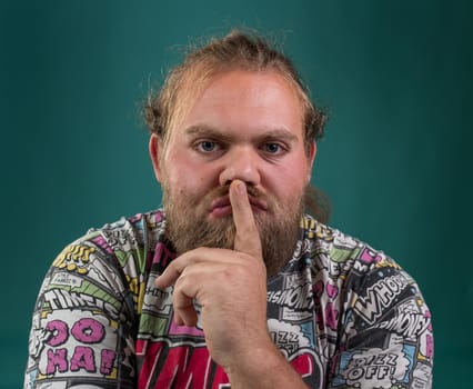 Bored man holding finger over mouth in studio