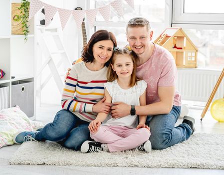 Happy family sitting together on floor in light room