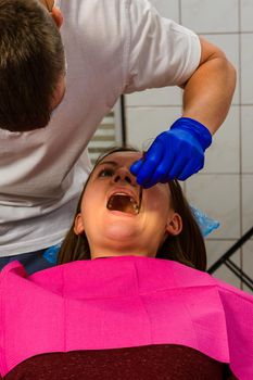 The dentist examines the oral cavity before treating the problem areas of the teeth.2020