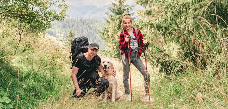 Young girl and man with dog trekking panoramic mountain