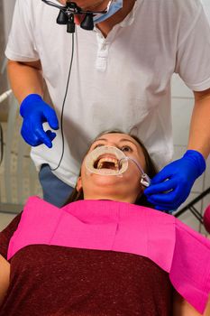 The dentist prepares the patient for the procedure of tartar removal by ultrasound, on the lips of the patient's retractor.2020