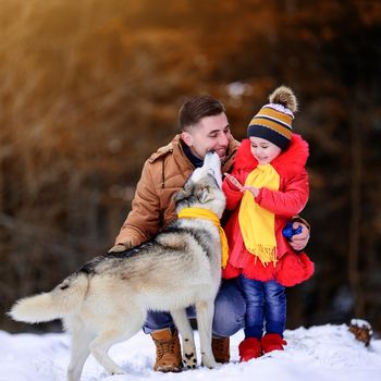 Happy father with daughter and their pet in winter park, walking with dog.new